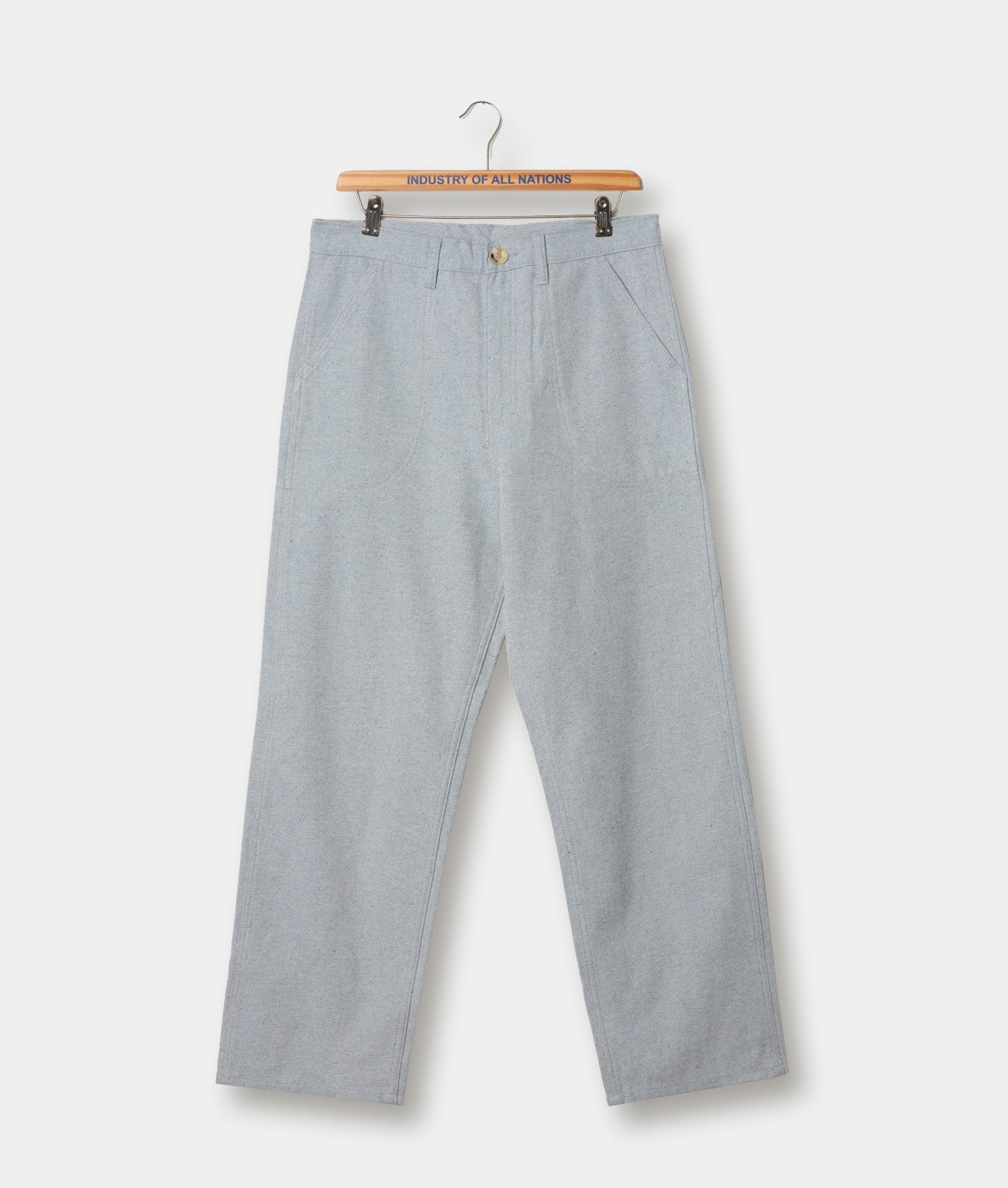 Light gray cotton chino trousers displayed on a wooden hanger with a "Industry of All Nations" branded label - Industry of All Nations