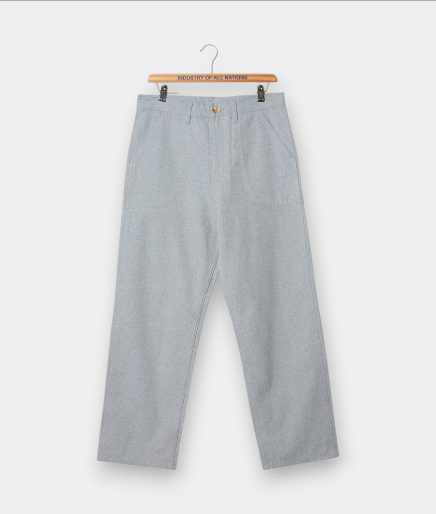 Light gray cotton chino trousers displayed on a wooden hanger with a "Industry of All Nations" branded label - Industry of All Nations