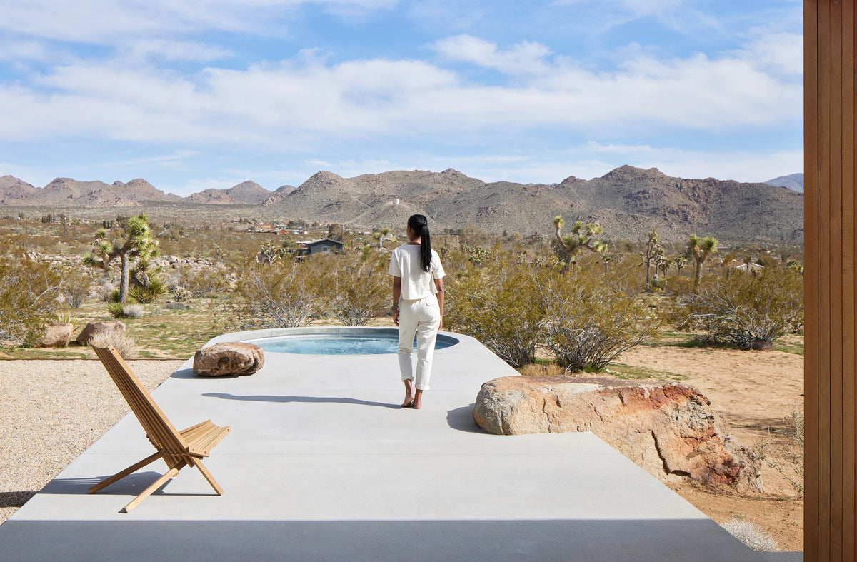 A guest on the terrace beside the circular plunge pool, overlooking the Joshua Tree landscape
