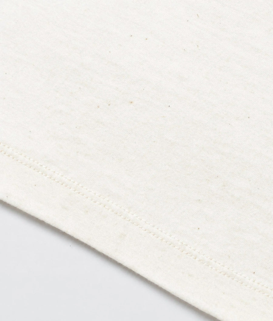 Close-up of a cream-colored fabric with a visible diagonal hem and fine knit texture.