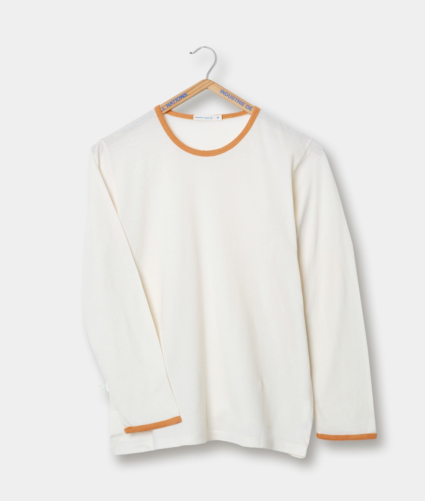 Cream-colored crew neck sweater with orange trim, displayed on a clothing hanger - Industry of All Nations