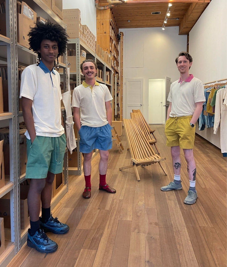 Three men wearing IOAN Sport Polo Shirts with contrasting collars, standing side by side inside the IOAN store.