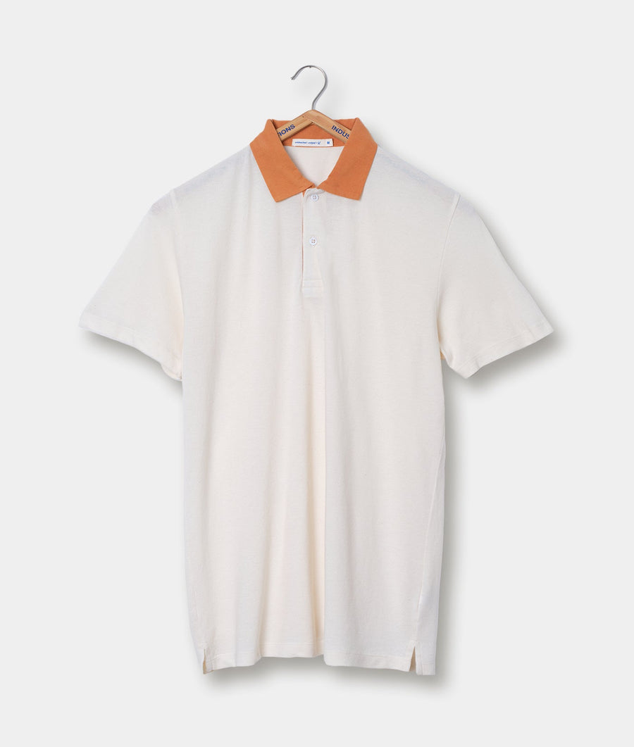 A white collared polo shirt with orange trim displayed on a hanger - Industry of All Nations