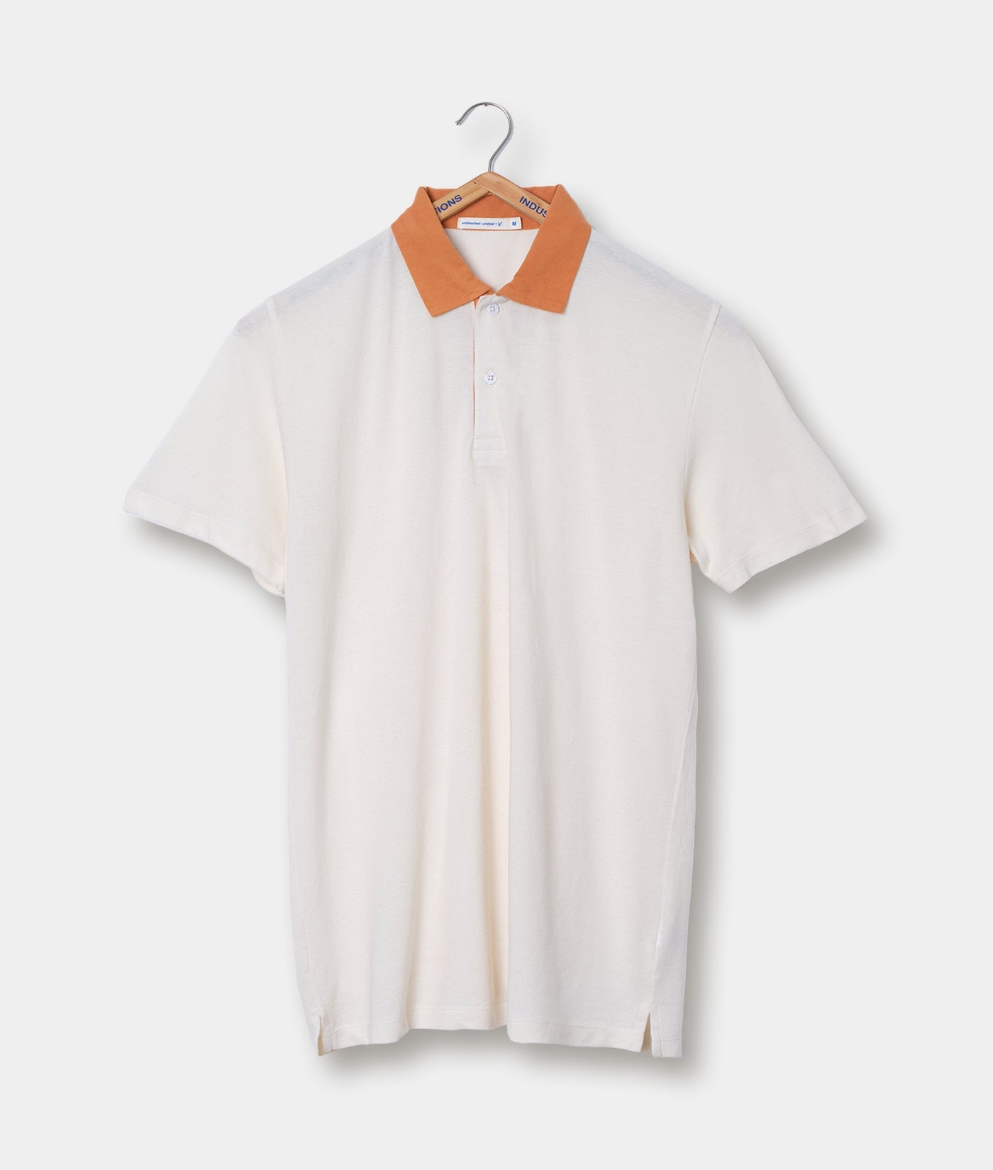 A white collared polo shirt with orange trim displayed on a hanger - Industry of All Nations