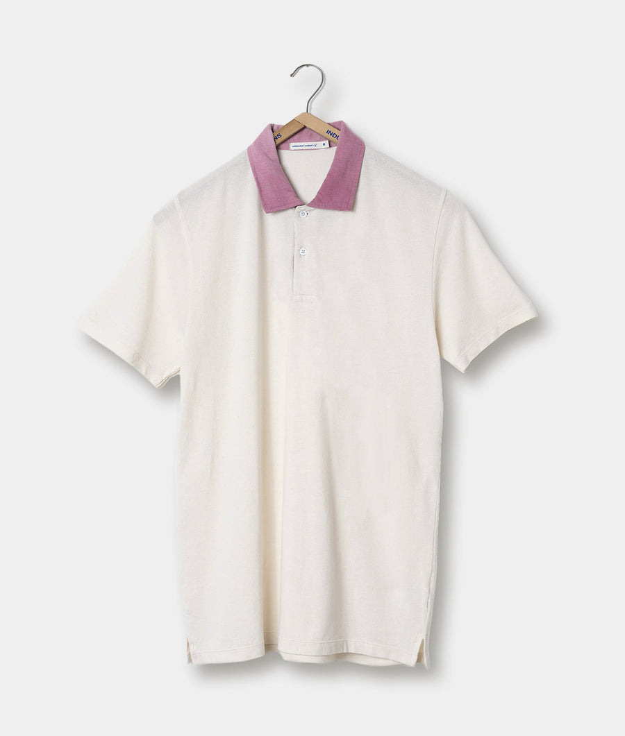 A white polo shirt with a pink collar displayed on a clothing hanger - Industry of All Nations