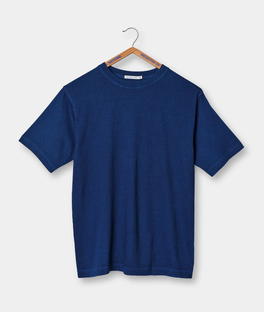 Blue cotton t-shirt hanging on a wooden hanger with blue and orange text labels - Industry of All Nations