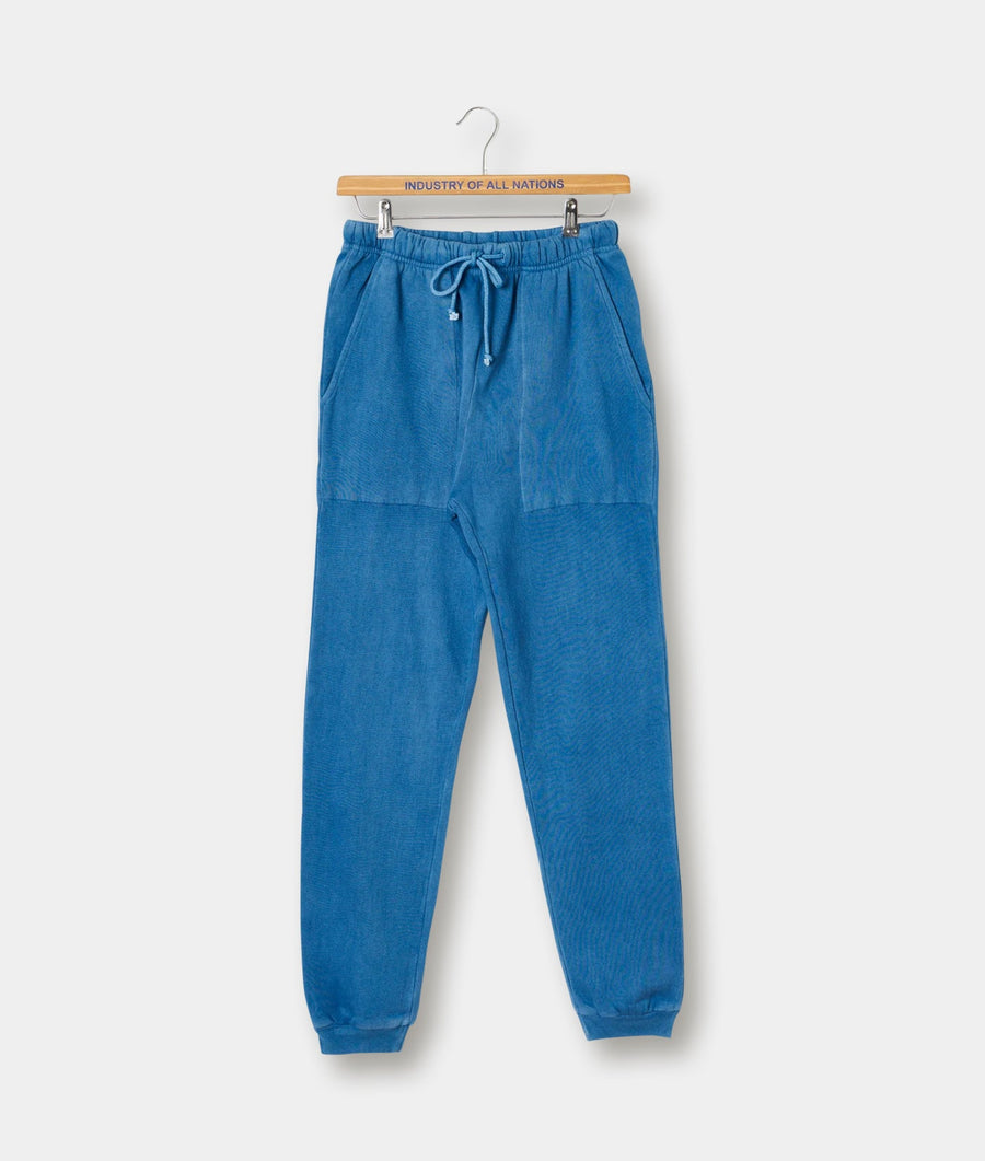 A pair of blue, drawstring waist cotton jogger pants displayed on a wooden hanger with "Industry of All Nations" text - Industry of All Nations