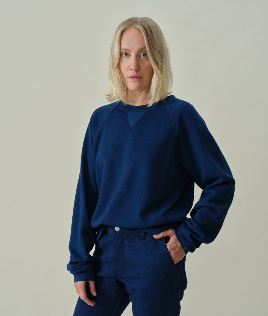 A young woman wearing a navy blue, oversized cotton sweatshirt against a neutral background - Industry of All Nations