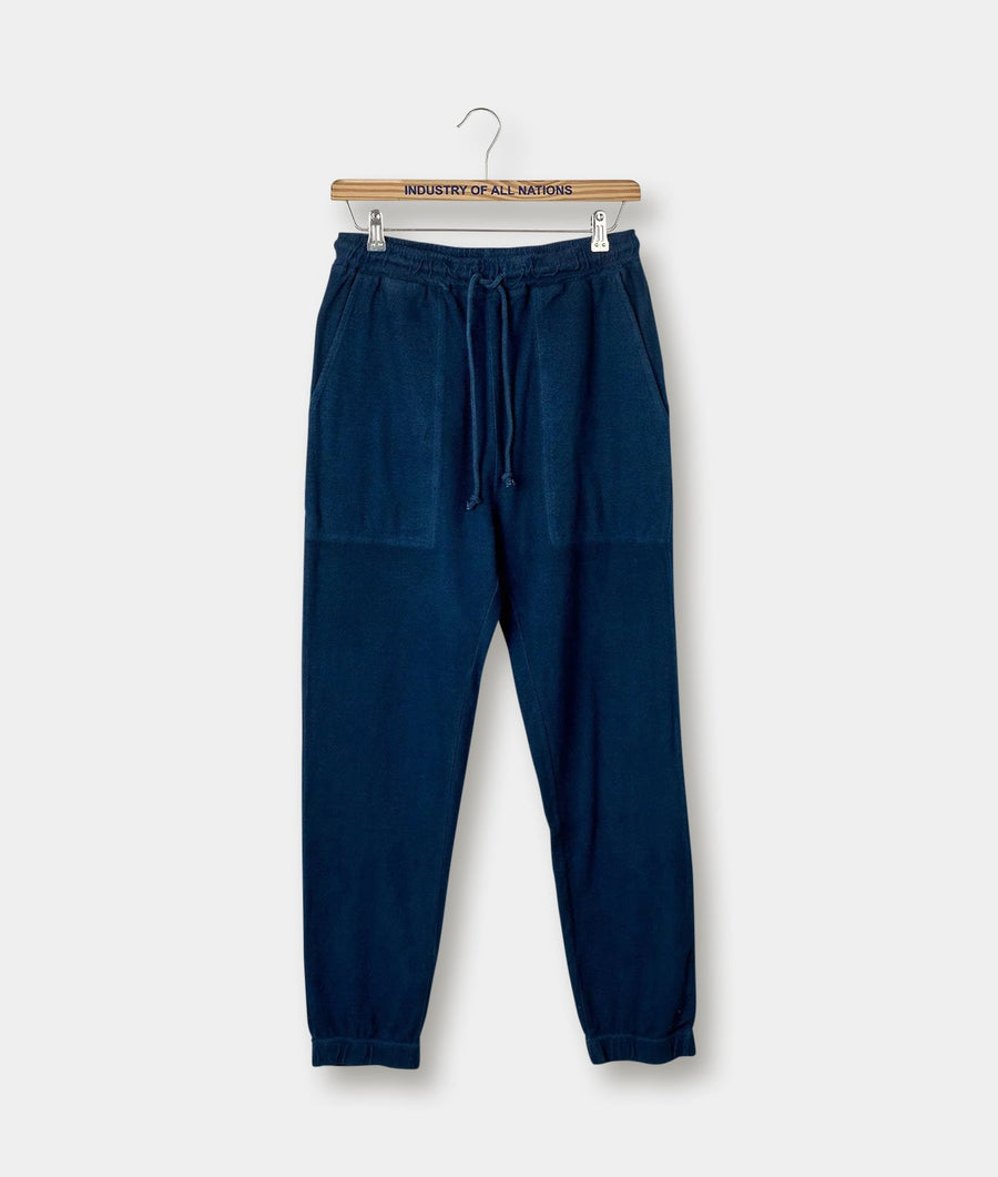 Navy blue cotton sweatpants with drawstring waist, displayed on a wooden hanger against a plain background - Industry of All Nations