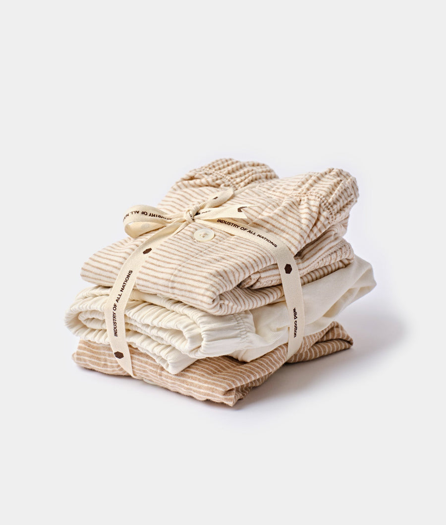 Stack of neatly folded beige and white striped organic cotton garments in a flat lay - Industry of All Nations