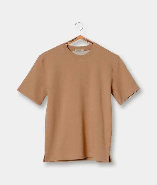Beige crew-neck t-shirt hanging on a hanger with the brand's "As Naciones Industrie" logo tag - Industry of All Nations