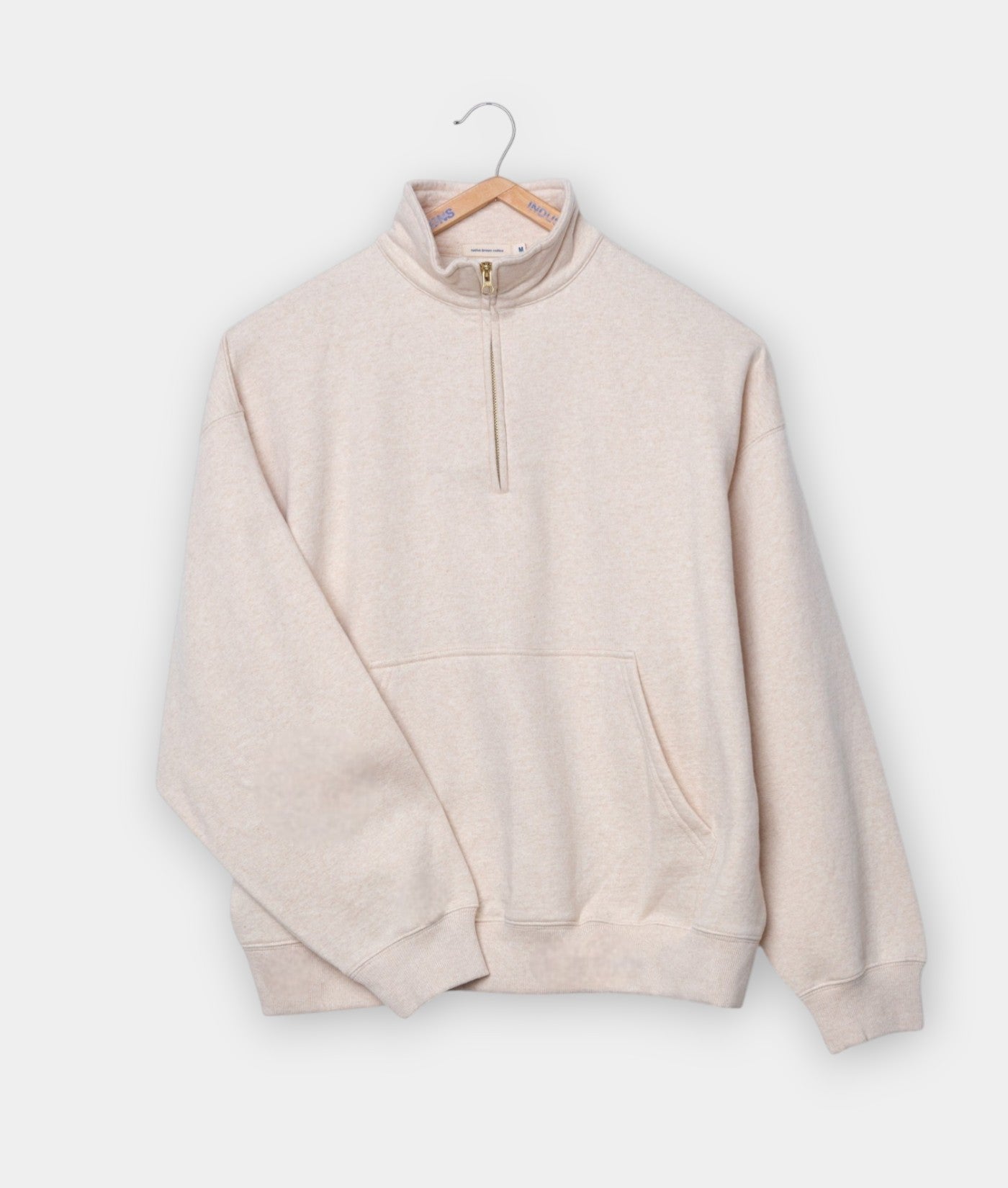 Beige fleece pullover with zipper, hanging on a wooden hanger - Industry of All Nations