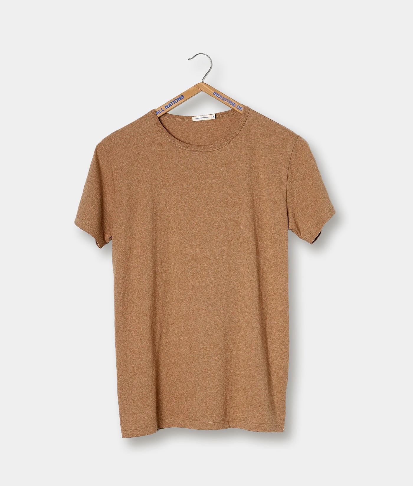 Tan colored T-shirt hanging on a black metal hanger with 'Industry of All Nations' branding - Industry of All Nations