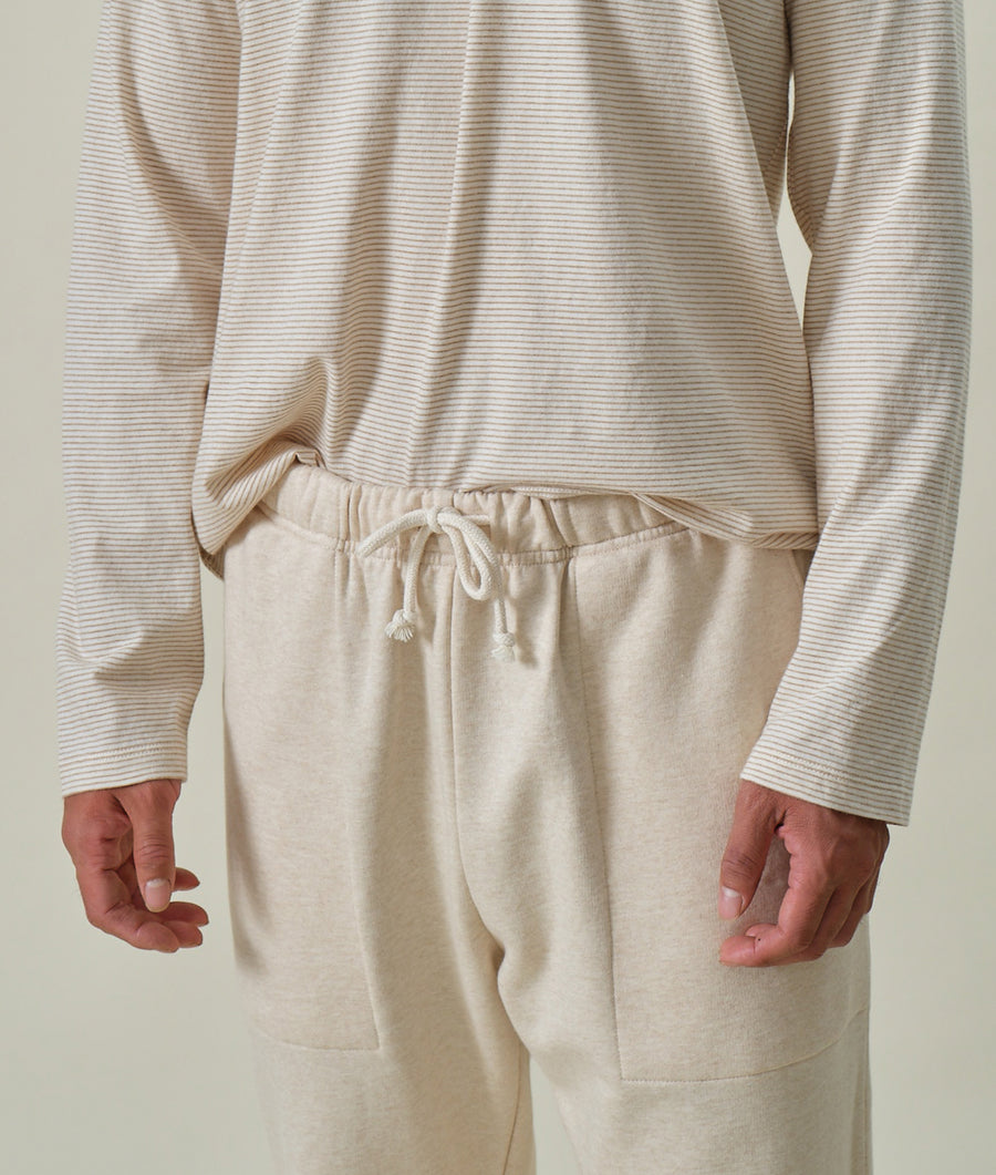 Close up of cream-colored organic cotton striped pullover with knit ribbed cuffs and hem, worn by a person - Industry of All Nations