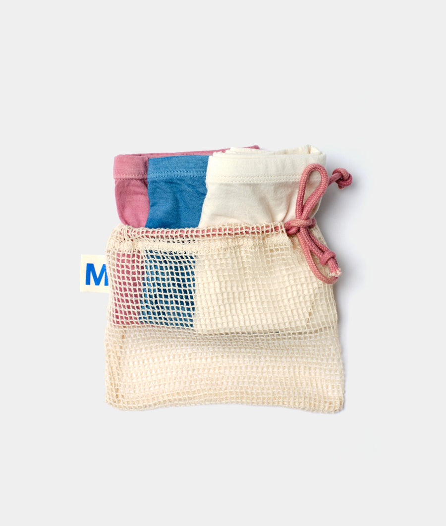 A reusable mesh produce bag made of natural cotton fibers, containing three colorful cotton underwear or swimwear items - Industry of All Nations