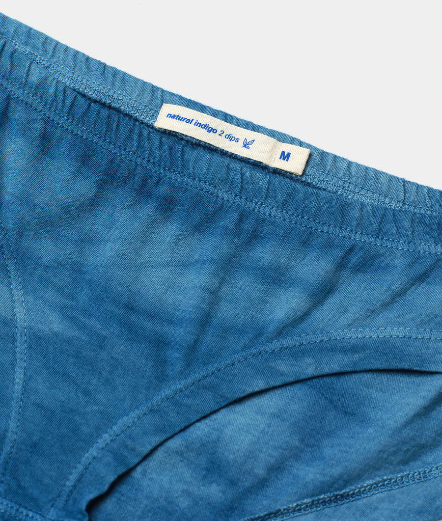 A close-up detail shot of the waistband of a pair of blue denim shorts with a "natural indigo 2 clips" label - Industry of All Nations